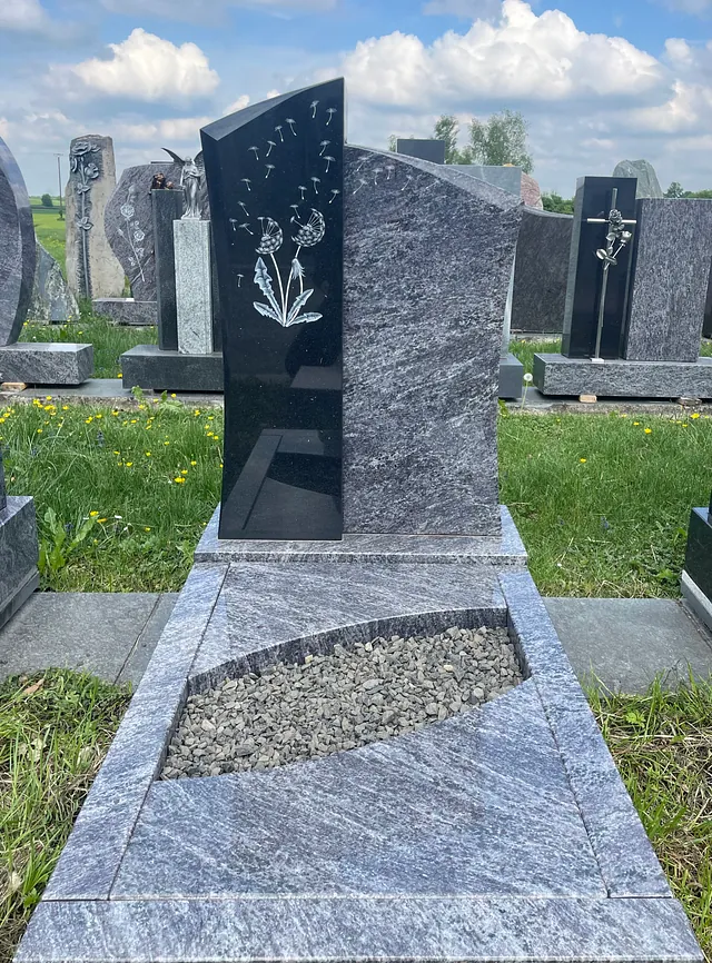 Graues Denkmal mit einer eingravierten Pusteblume