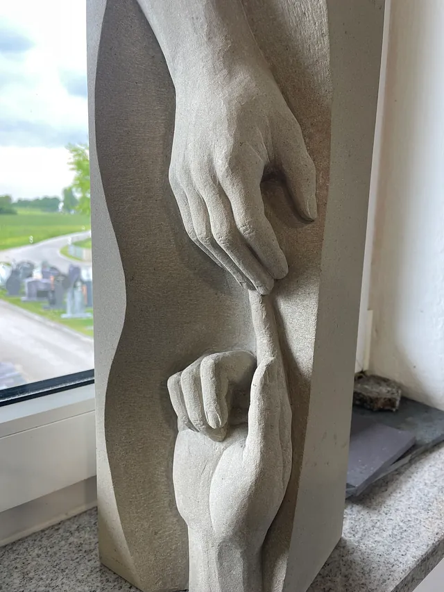 Motiv in Sandstein, zwei Hände, die sich berühren