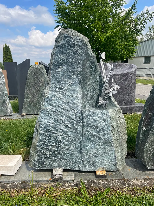 Grabstein mit Grashalmen aus Metall und Schmetterlingen drauf